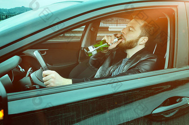 一个醉汉开车，手里拿着一瓶<strong>酒</strong>。开车时喝啤<strong>酒</strong>的人。