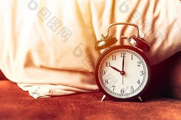 闹钟放在床上的枕头上，用于睡眠时间唤醒计时器的概念。