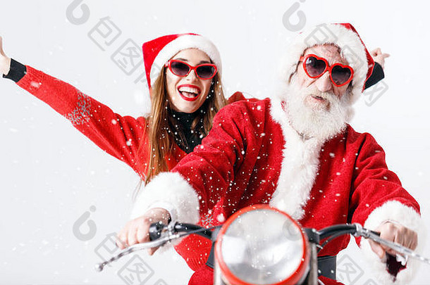 圣诞老人老人白色胡子穿sungasses年轻的夫人老人穿圣诞老人他红色的毛衣太阳镜骑摩托车一年圣诞节假期记忆礼物购物折扣商店雪少女圣诞老人老人化妆发型狂欢节