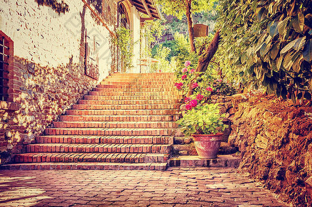 美丽的老街，用鲜花和小砖块装饰的房子附近的老式楼梯，在意大利散步的浪漫之地