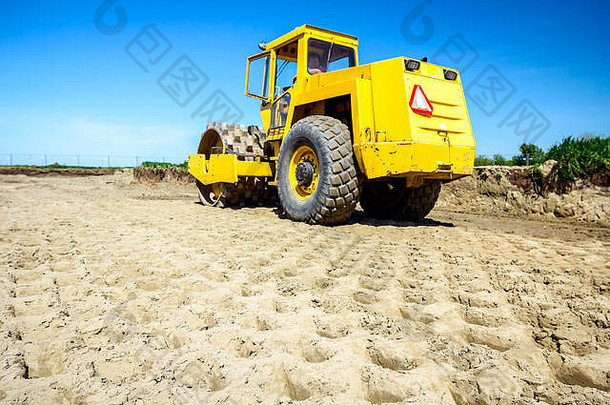 带钉子的巨大压路机正在建筑工地压实土壤、沙子。