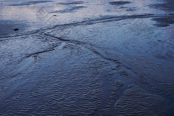 冰岛西部Borgarfjörður泥滩的抽象形状，在冬季昏暗的光线下呈现出深沉的颜色