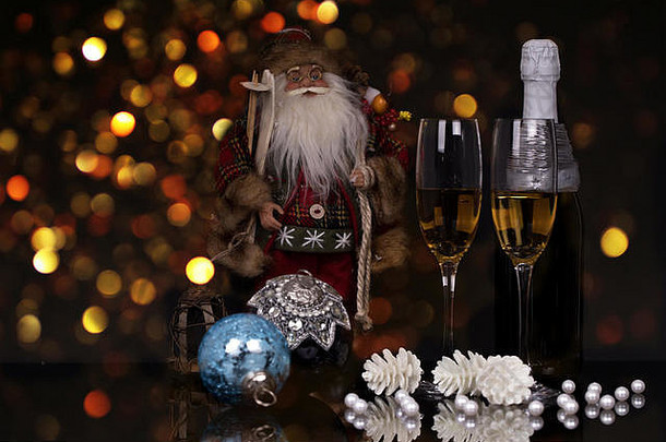两个酒杯，香槟酒，圣诞老人和圣诞装饰品，黑色背景，反光。空间。圣诞快乐，新年快乐
