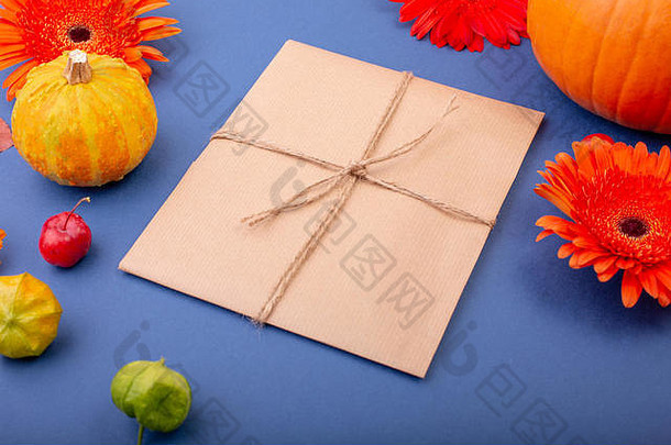 手工礼品盒的俯视图，蓝色背景上有黄色和橙色的花朵和南瓜。空白贺卡的创意工作设计。平铺