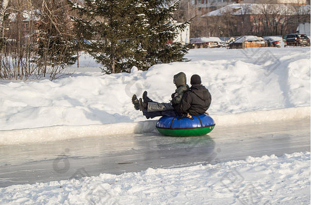 孩子们在充气管上乘坐冰滑梯，在滑冰上高速滑梯，在宾夕法尼亚州的城市里进行冬季娱乐和户外活动