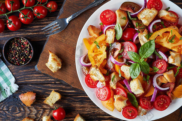 美味的新鲜的经典意大利沙拉潘扎内拉西红柿油炸面包丁罗勒洋葱环白色板木表格成分
