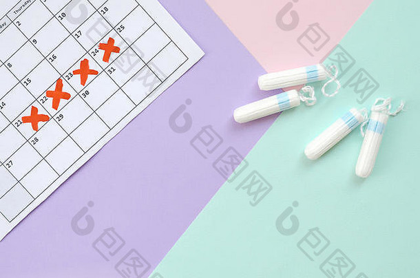 在蓝粉色和淡紫色的粉彩背景上，用日历和月经棉条组成的平铺构图。妇科概念。关键日pms周期项目
