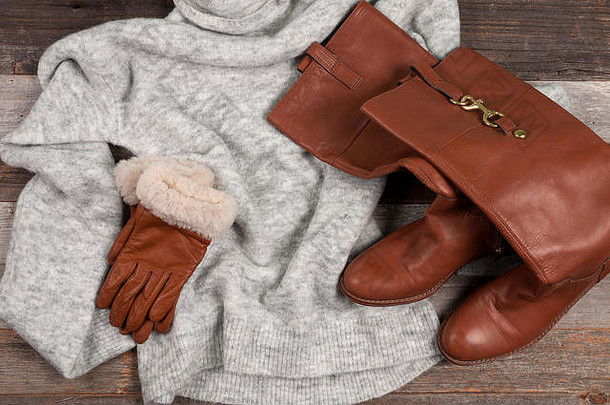 圣诞节的气氛。冬衣在木制桌子背景上编织温暖的毛衣、手套和靴子。