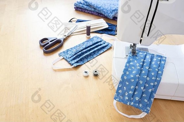 缝纫机上的<strong>社区</strong>布面罩和木桌上的剪刀、纱线和织物等实用工具，的防疫措施