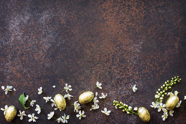 复活节的概念。彩色复活节背景，巧克力蛋和盛开的鸟樱花镶嵌在石头或石板背景上。