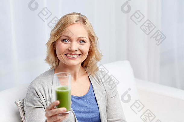 在家喝绿色果汁或奶昔的快乐女人