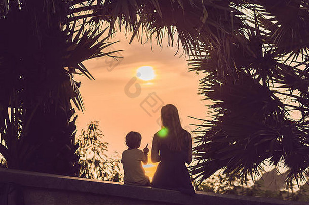 轮廓妈妈。儿子满足日落热带地区背景棕榈树