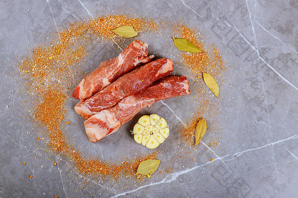 新鲜的肉，大蒜，香料和生鱼片放在花岗岩炊具的砧板上。顶视图。