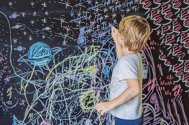 小男孩指着墙上的太空、行星和星星