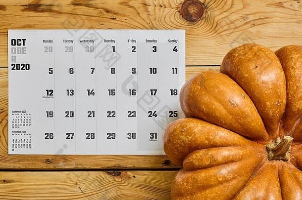 简单的2020年十月月历，放在木桌上，上面放着一个南瓜