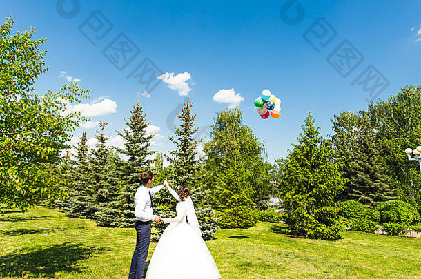 新娘和新郎在蓝天上看气球