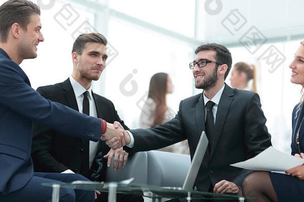 合作伙伴在团队成员面前完成交易并握手
