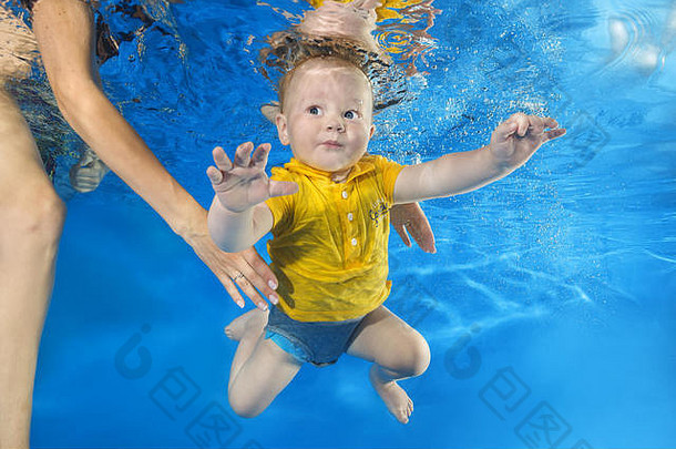 妈妈教一个穿黄衬衫的小男孩在游泳池里游泳