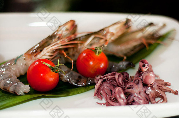 生虾、西红柿和章鱼放在盘子里