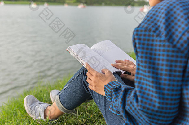 年轻的女孩坐着草阅读书