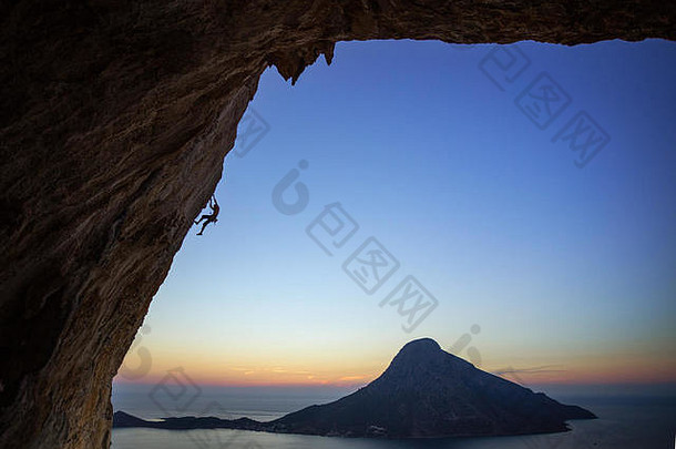日落时悬崖峭壁上的攀岩者。希腊卡利马诺斯岛。