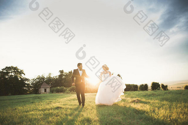 一对时尚的新婚夫妇在婚礼当天带着花束在公园散步