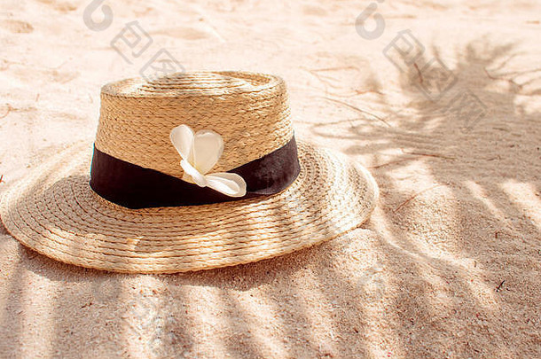 沙上草帽，防晒理念。戴着帽子和棕榈叶的静物画，岛上的海滩度假。