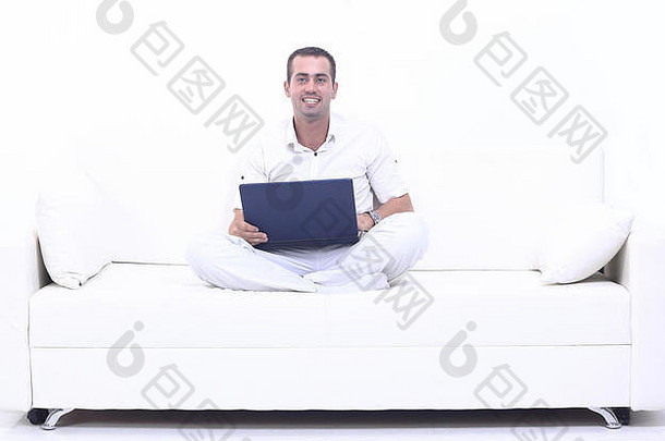 坐在沙发上用笔记本电脑工作的男人