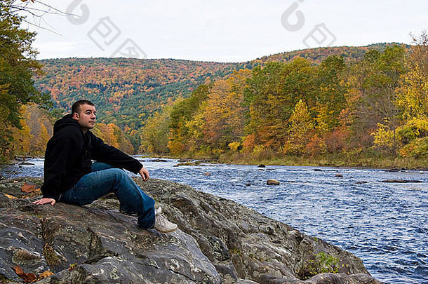 年轻的男人。享受和平美丽的网站听起来佛蒙特州河峰秋天树叶