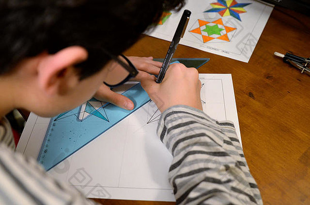 都灵，皮埃蒙特，意大利。2019年4月。一个戴眼镜的黑发白人男孩正在做技术制图作业。带指南针，尺子，正方形，它是cre