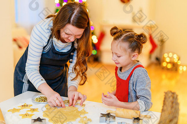 圣诞前夜，一家母女在家烤饼干。装饰精美的房间、壁炉、圣诞树和背景灯