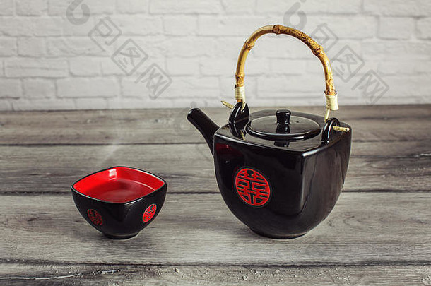 放在灰色木桌上的红茶壶和方杯，盛满了热茶，上面有红色的中国印章，意为双喜<strong>临门</strong>。