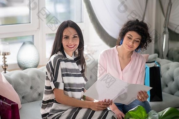 两个黑发女人坐在美容院查看价目表