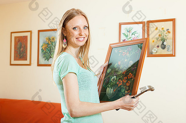 幸福的女人把艺术画挂在房子的墙上