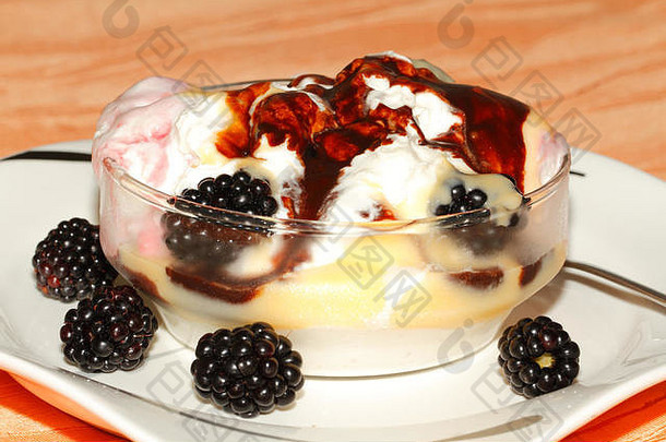 各种口味的冰淇淋，在一个小碗里放有鲜奶油、巧克力酱、蛋酒和黑莓