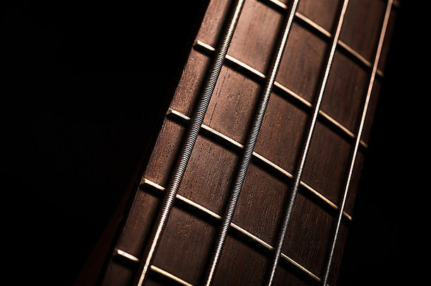 黑色背景上低音吉他的fret板细节。