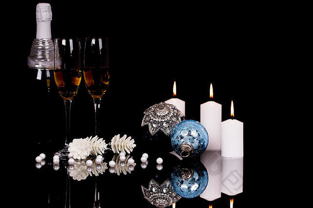 两个酒杯，香槟，圣诞装饰品和蜡烛，黑色背景，反光。空间。圣诞快乐，新年快乐