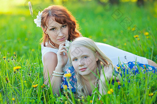 年轻的母亲和她的小女儿在草地上玩耍