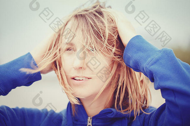 在户外刮风的夏秋秋日，一位年轻的白人白人女女孩带着凌乱的头发向外张望的特写照片，用Instagram滤镜进行了色调调整