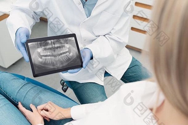 牙科门诊咨询。牙医在数字平板电脑屏幕上显示牙齿x光片
