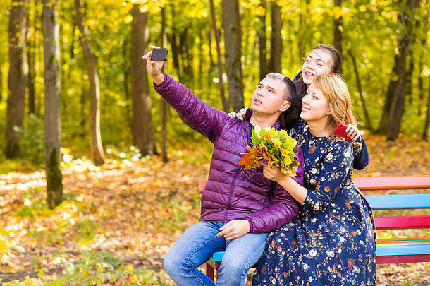 家庭、季节、科技和人的概念-秋天公园智能手机自拍的快乐家庭