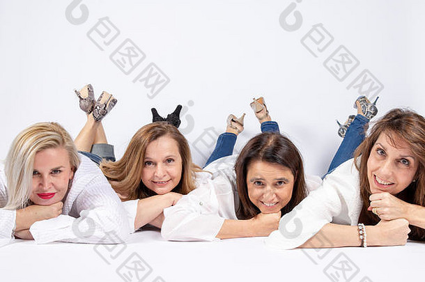 在摄影棚里给四个躺在白色背景地板上的朋友拍照。