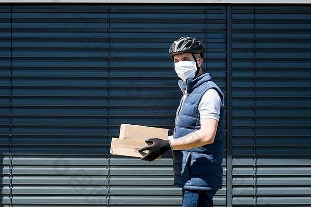 带口罩的快递员递送包裹、电晕病毒和检疫概念。
