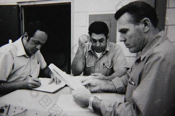 三位专业人士举行战略会议的70年代经典黑白生活摄影精品。
