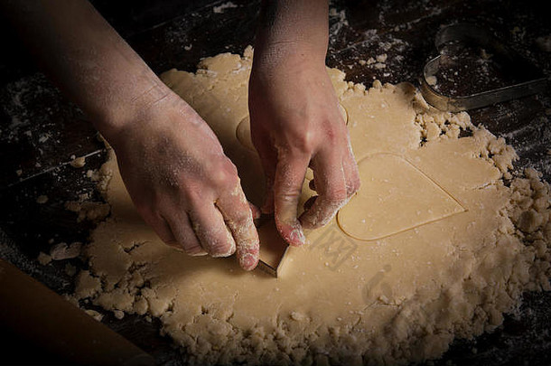 情人节烘烤，女人从面团中切出心形饼干。