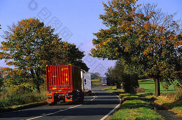 英国利兹约克郡附近，卡车穿过秋色树木在公路上行驶