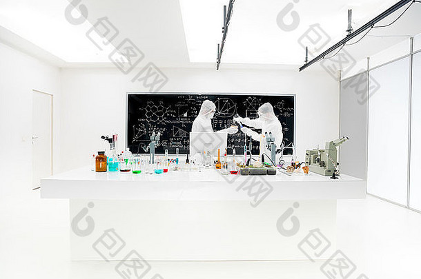 两位科学家在一个化学实验室的特写镜头，他们在一张实验桌旁用五颜六色的液体、实验工具和m