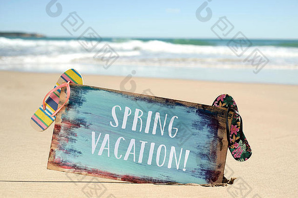 一个乡村招牌的特写镜头，上面写着“春天假期”和一些彩色的人字拖，在一个安静海滩的沙滩上，大海在我的脚下