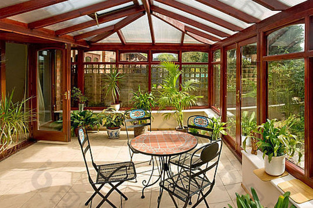 温室里的桌子、椅子和花园旁边的房间里的植物
