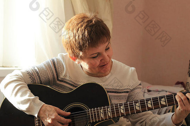 在家弹吉他的中年妇女